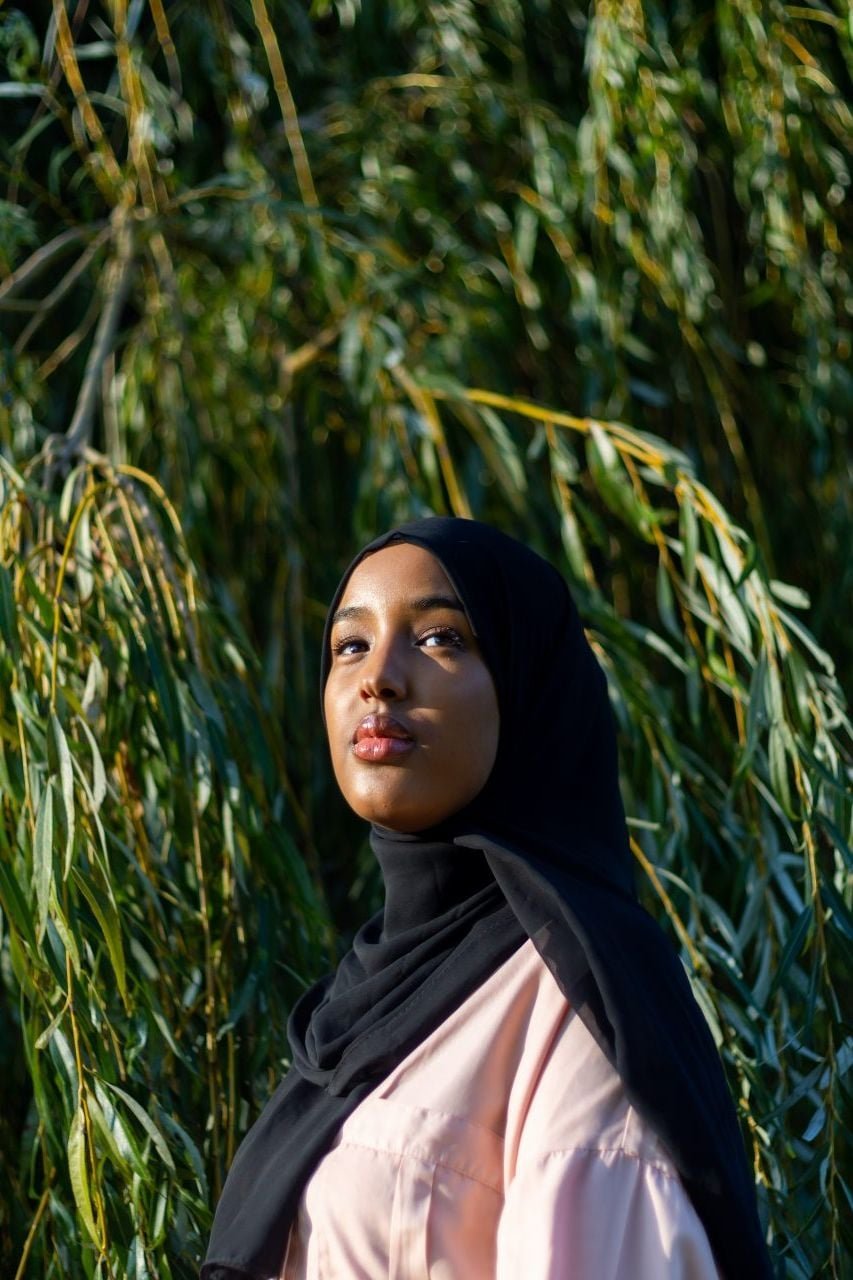 A woman wearing a hijab stood in front of a tree