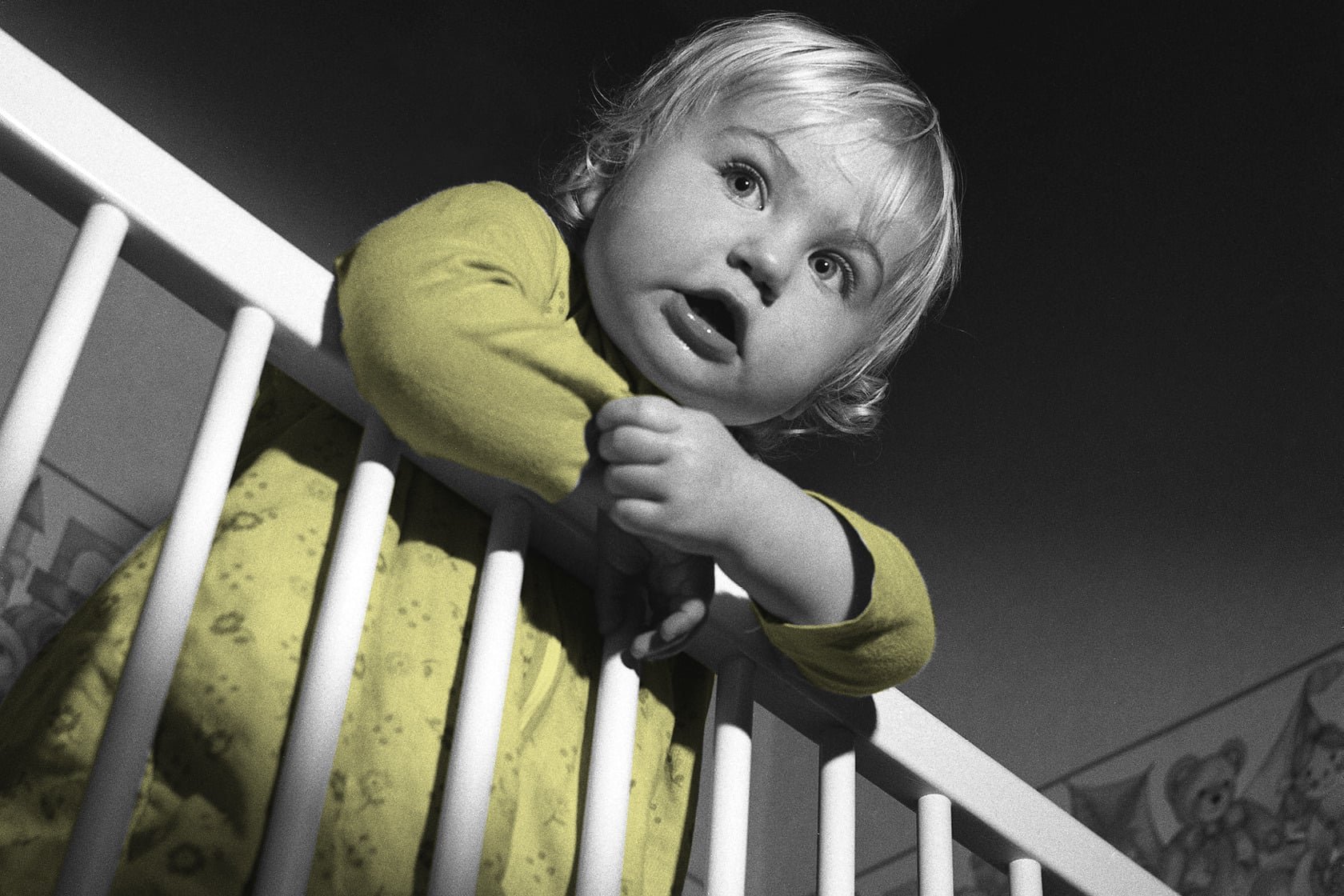 A baby hanging over a cot