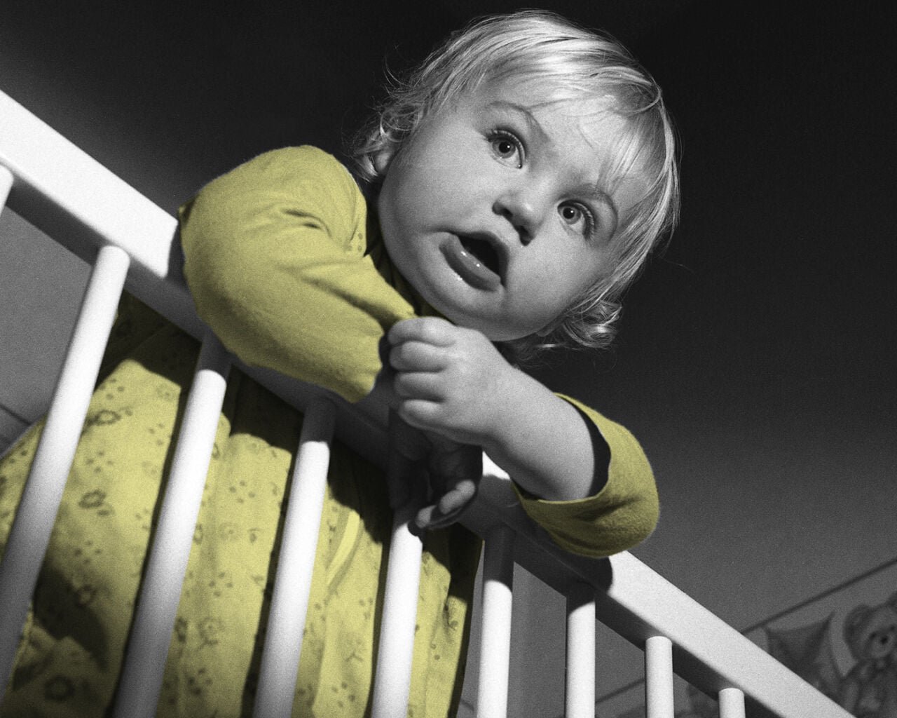 A baby hanging over a cot