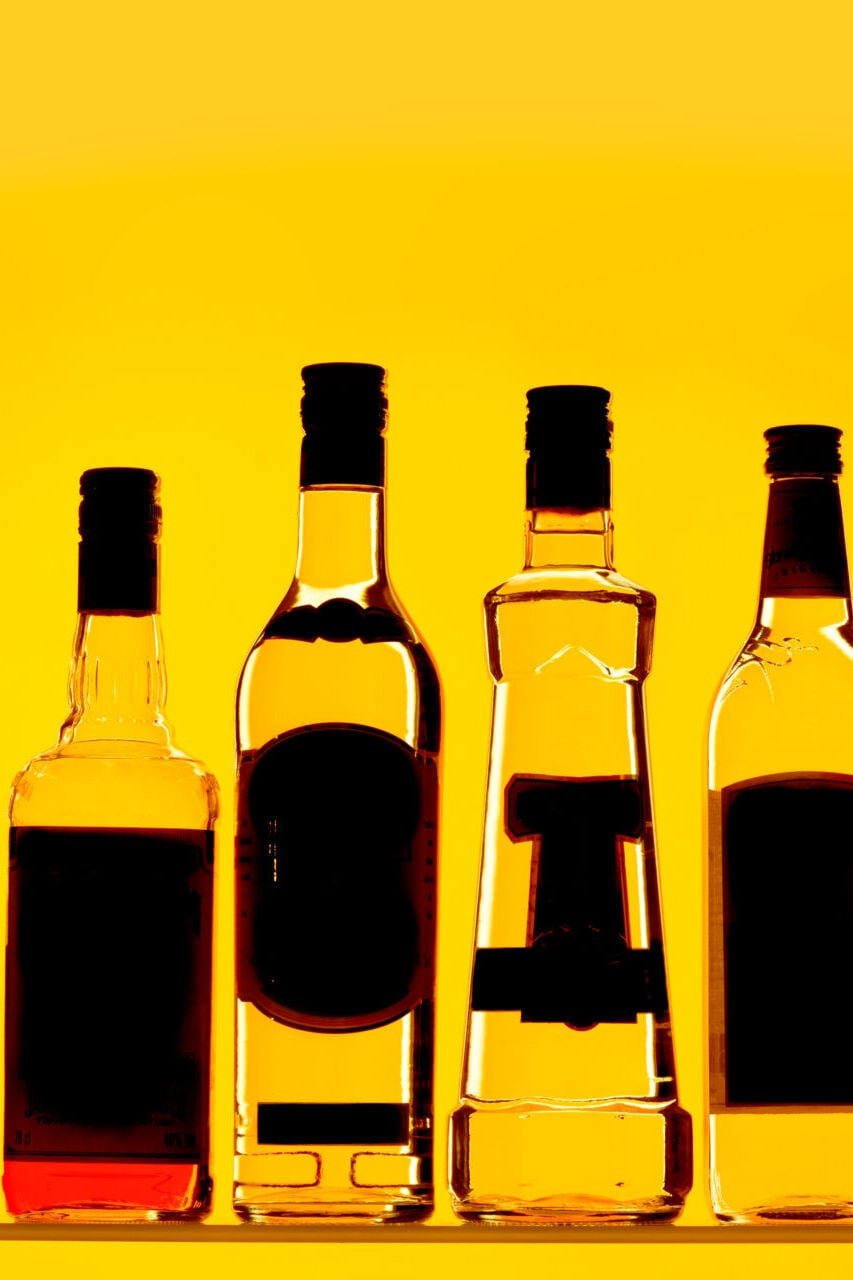 A selection of alcohol bottles on a yellow background