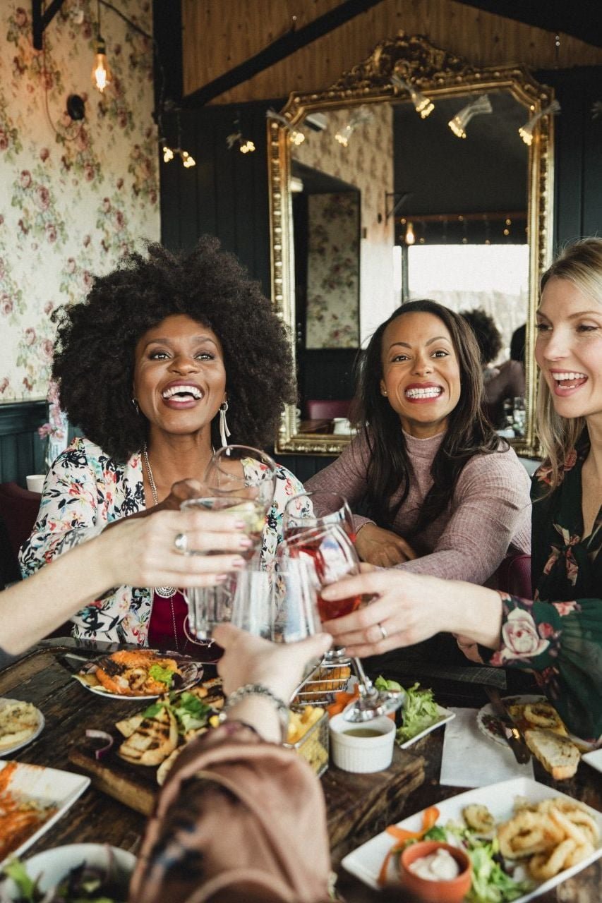 An over the shoulder shot of a group of beautiful mid-adult women enjoying a celebratory toast together in a bar