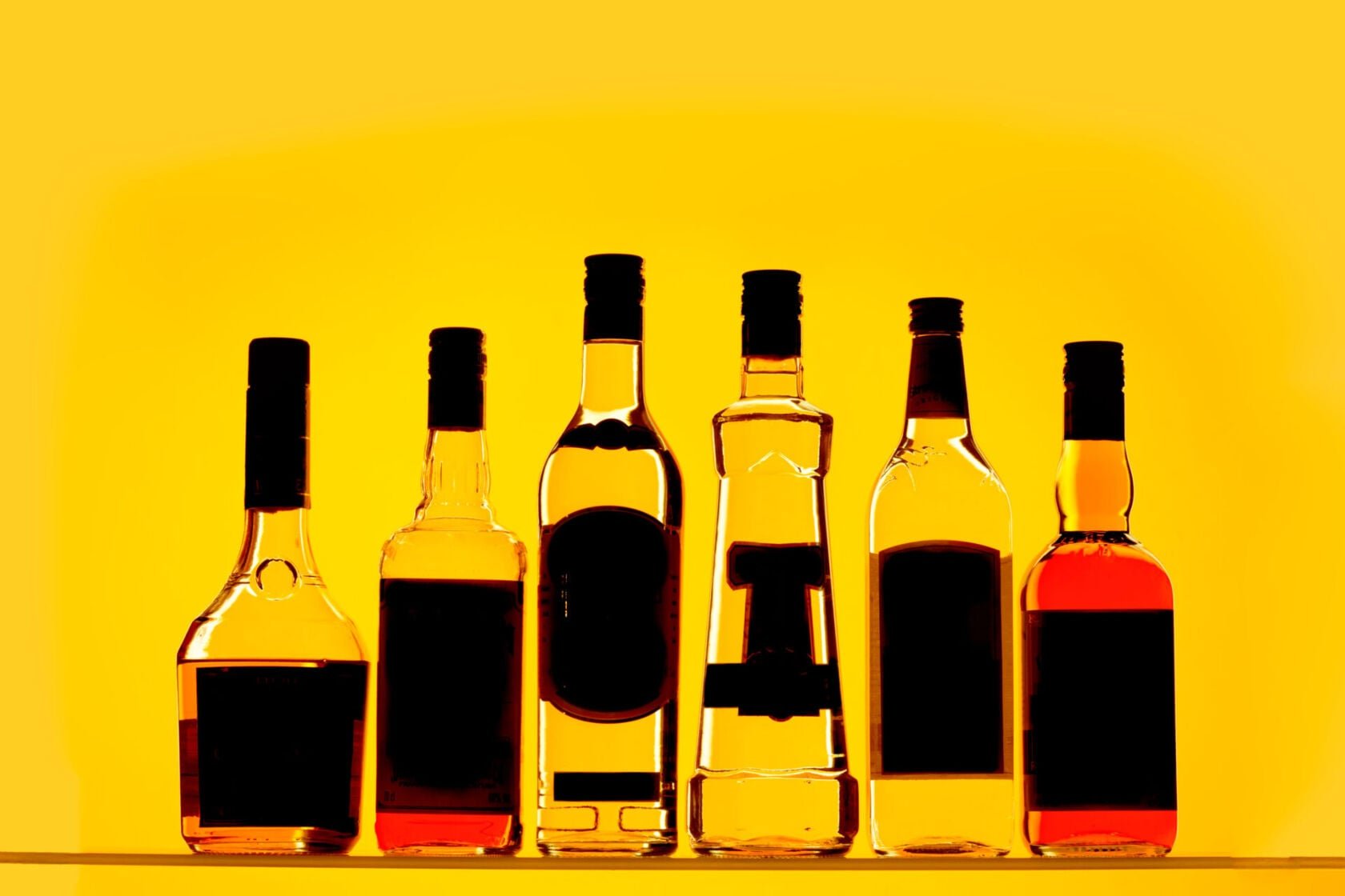A selection of alcohol bottles on a yellow background