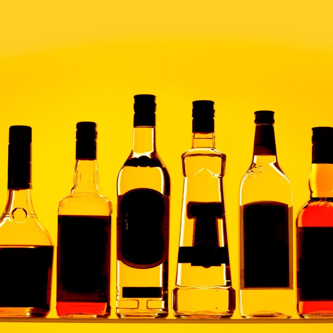 A selection of alcohol bottles on a yellow background