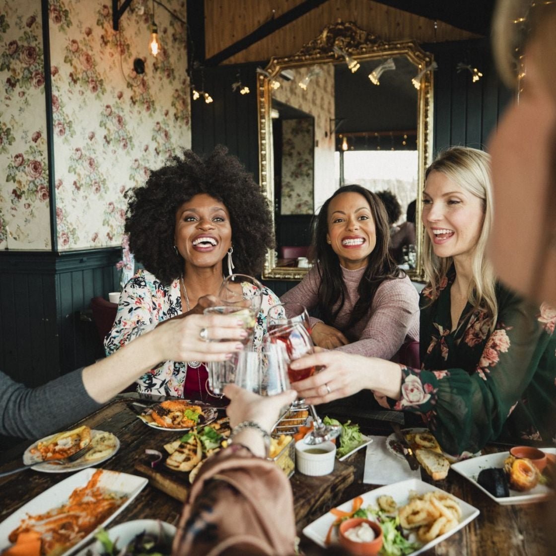 An over the shoulder shot of a group of beautiful mid-adult women enjoying a celebratory toast together in a bar