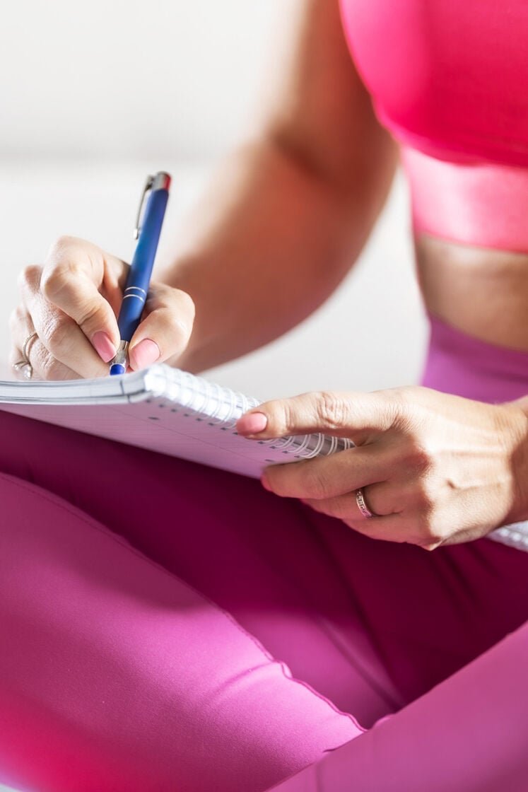 Woman writing out fitness goals